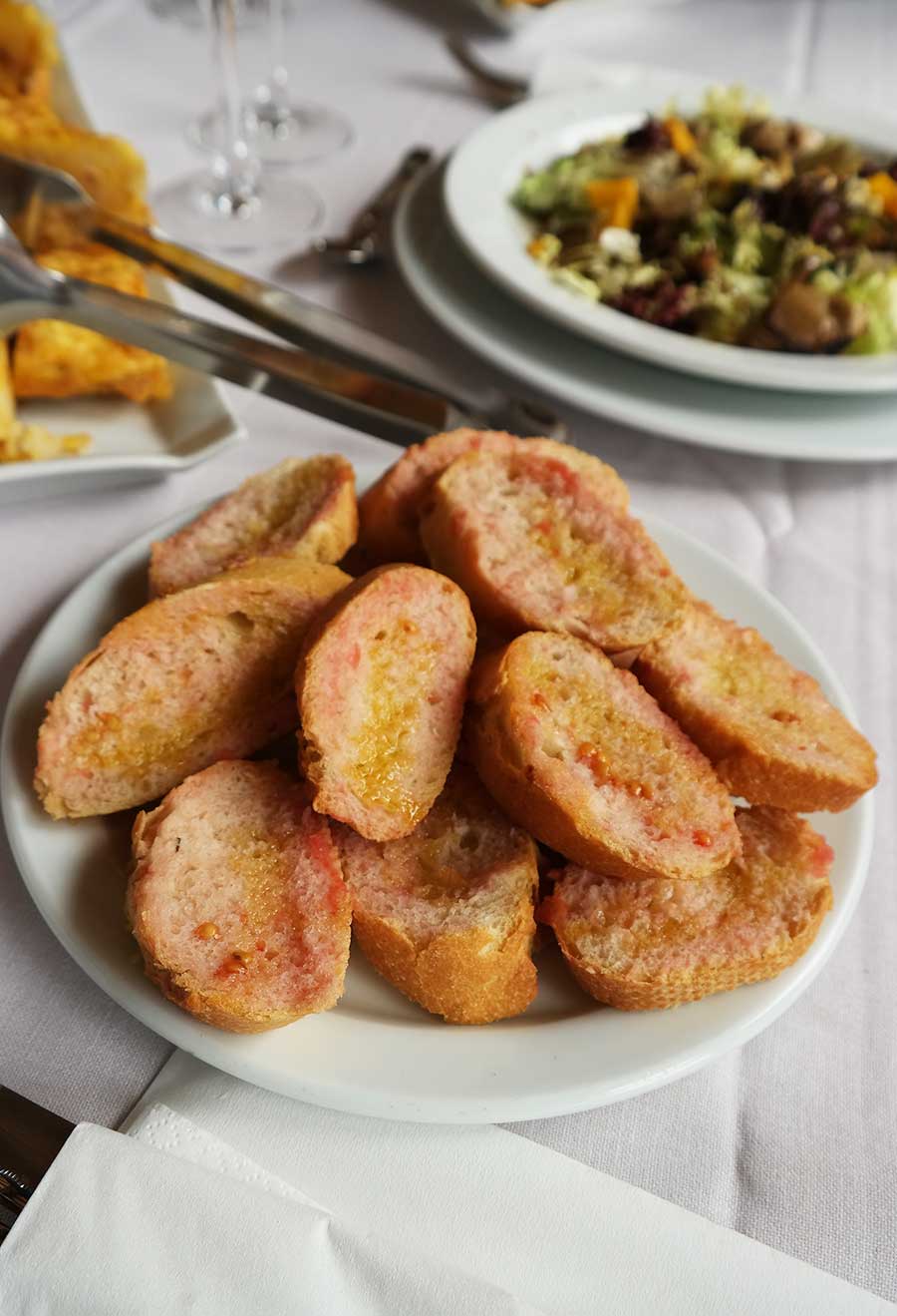 When you are planning your Garnacha Day soiree, add this Catalan recipe in your menu. It's as authentic as it gets, tastes amazing, and it's budget-friendly. Pa amb tomàquet is simply bread with tomato, known as Spanish Toast, or Catalan Toast. It is a common dish in Catalonia, even moms make it for lunch for the kids, and while it is a humble everyday dish, the Catalan tomato toast is also served on finer dinners, and it is eaten any time of the day. It was a signature dish that we were served on almost any meal during our wine trip around the region. 